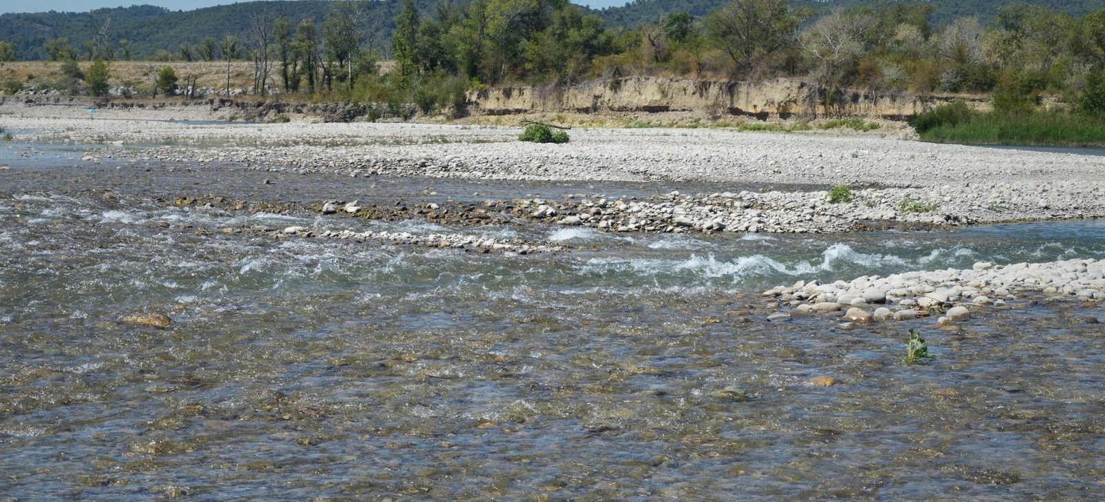 A shallow braided river running over a wide gravel bed