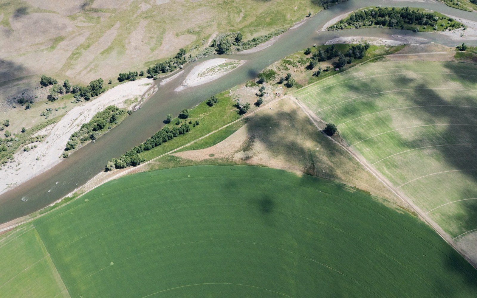 An oblique aerial view of a river bend between green fields