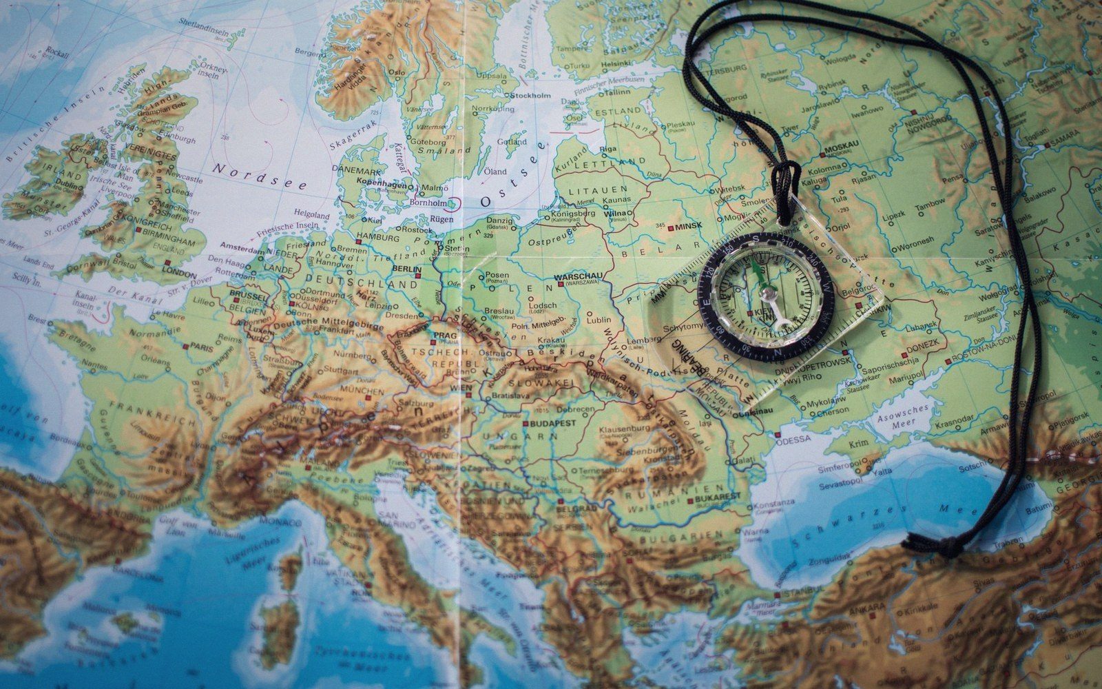 A pocket compass lying on a physical relief map of Europe