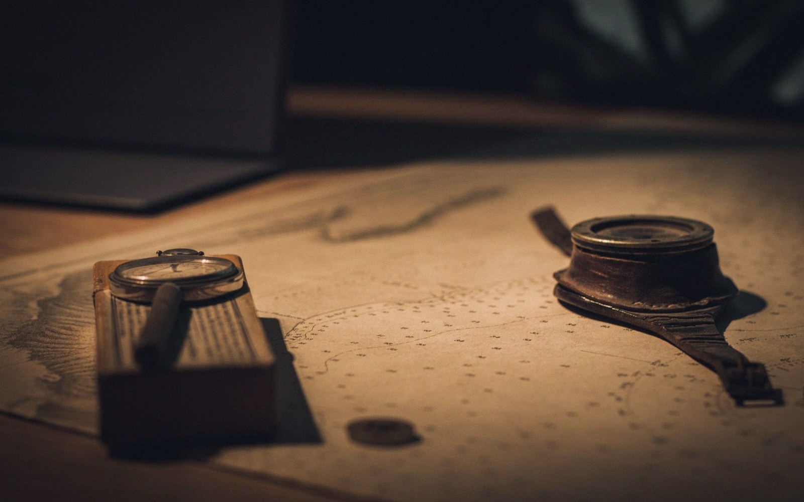 A magnifier and inkwell resting on a chart in low light