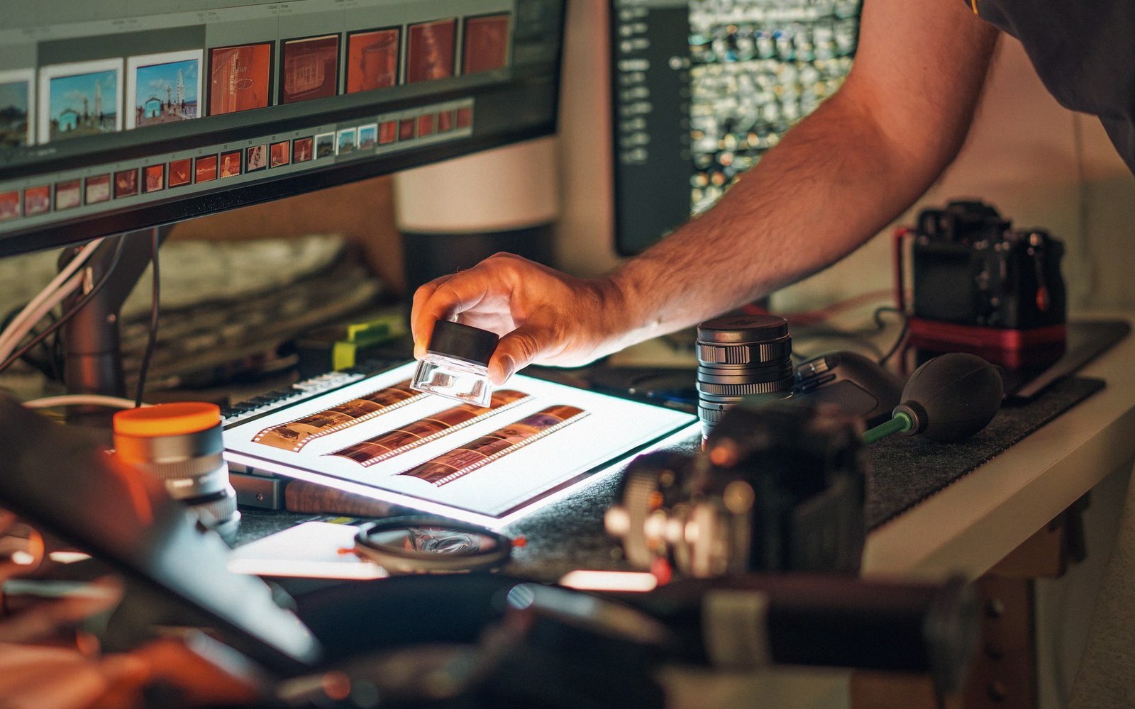 Hands working at a lit instrument bench, control panels behind