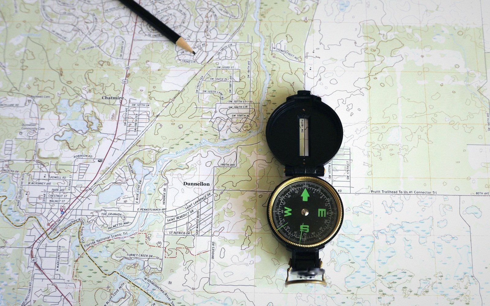 A lensatic compass resting on a folded topographic street map